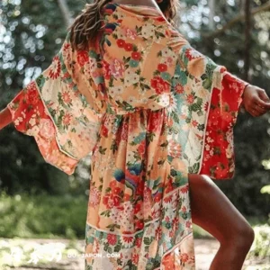 Femme en kimono floral coloré, dans un cadre naturel ensoleillé, exprimant joie et liberté.