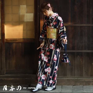 Femme en kimono floral traditionnel avec obi doré dans un intérieur japonais chaleureux.