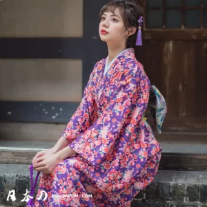 Femme en kimono floral, réfléchissant paisiblement dans un jardin japonais traditionnel.