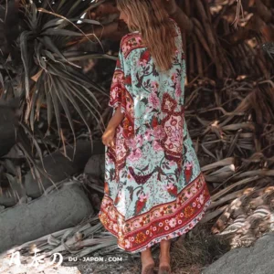 Femme en kimono floral, entourée de plantes tropicales, évoquant la détente à la plage.