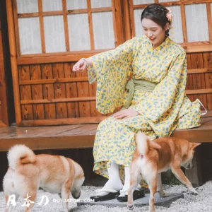 Femme en kimono jaune souriant avec des chiens dans un jardin japonais paisible.