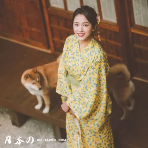 Femme en kimono jaune souriante avec un Shiba Inu sur un porche japonais.