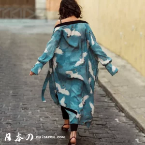 Femme en kimono turquoise marchant sur une rue pavée, élégance et tradition moderne.