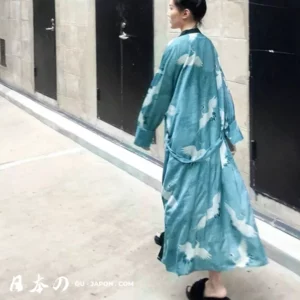 Femme en kimono turquoise élégant, ornée de grues, marchant avec grâce dans un cadre moderne.