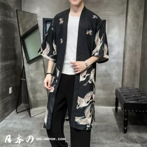 Homme en kimono noir moderne dans un intérieur minimaliste, alliant tradition et style contemporain.