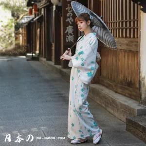 Femme en kimono blanc dans une rue historique, sous un parasol élégant.