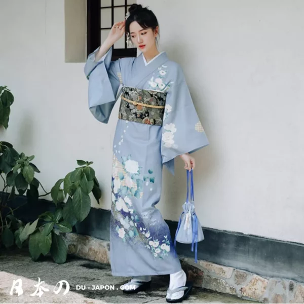 Jeune femme en kimono bleu floral, élégance et sérénité dans un cadre minimaliste.