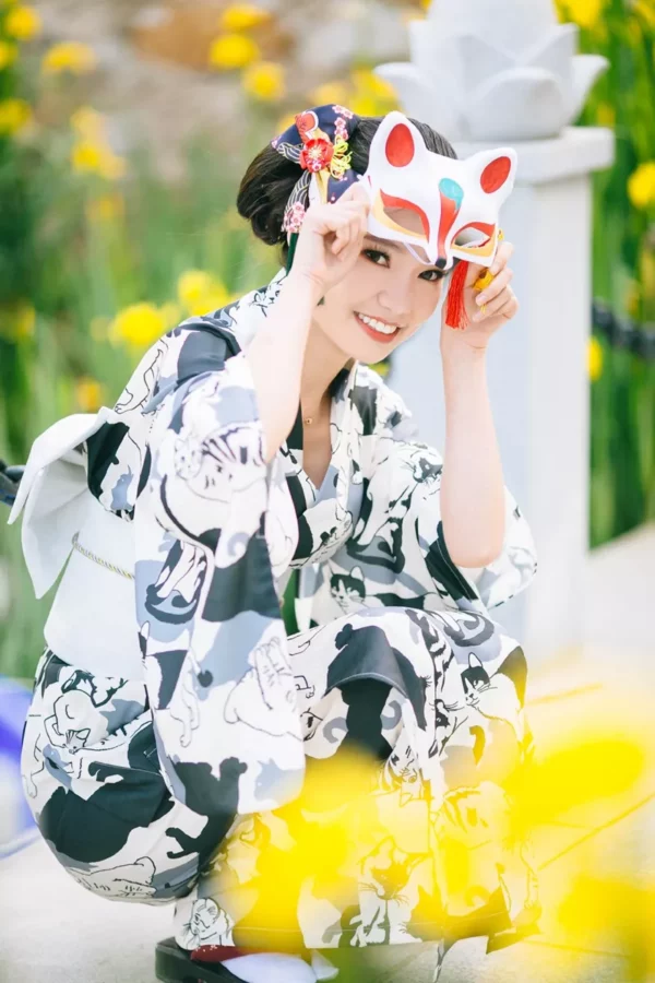 Femme en yukata traditionnel japonais avec masque de renard, entourée de fleurs vibrantes.