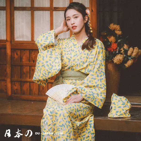 Femme élégante en kimono jaune, assise dans un cadre traditionnel japonais, avec éventail.