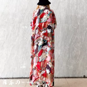 Femme en kimono rouge pastel avec chapeau noir, alliant tradition et modernité.