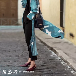 Mode urbaine : kimono turquoise avec motifs de grues blanches sur rue pavée.