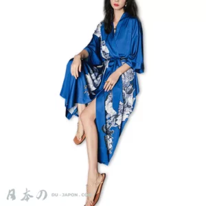 Femme sereine en kimono bleu élégant, robe chic et fleurie, ambiance relaxante.