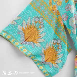 Kimono plage en tissu turquoise avec motifs floraux colorés et joyeux.